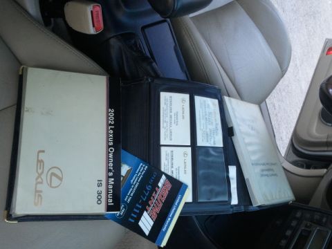 2008 Subaru Legacy - Car interior with owner's manuals and documents, including a 2002 Lexus IS 300 manual.