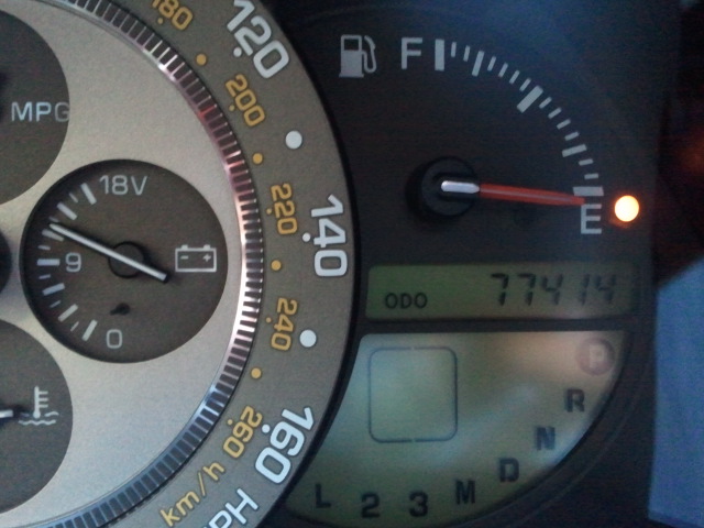 Car dashboard with speedometer, fuel gauge, and odometer showing 77414 miles