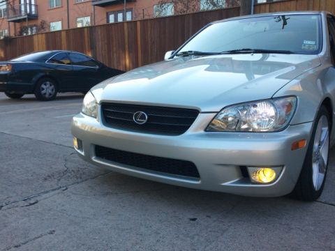 2008 Subaru Legacy - A silver Lexus sedan is parked in front of a wooden fence, with another car in the background. The license plate area has text.