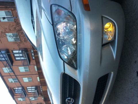 2008 Subaru Legacy - Front corner of a silver sedan, its grille and headlight, with a building in the background.