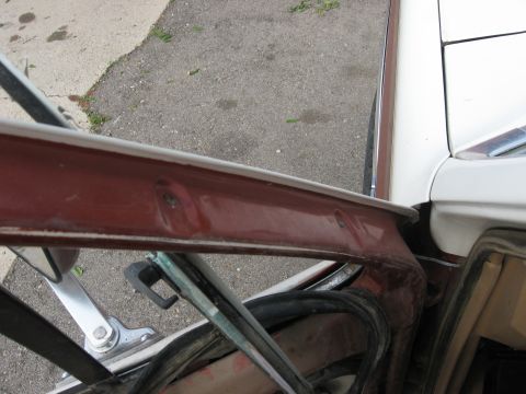 1981 Ford Bronco - Detail of the door frame and window seal on a vehicle, with exterior paint visible.