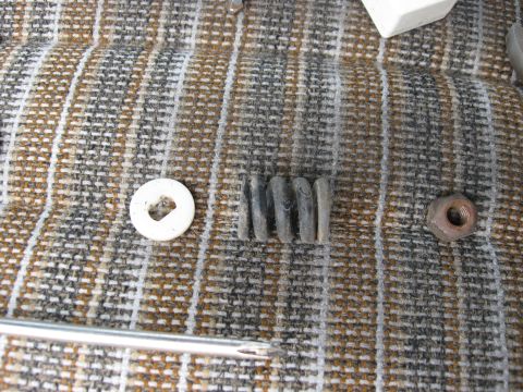 1981 Ford Bronco - A collection of assorted automotive hardware, including a washer, grommets, and a nut, laid out on a textured surface.