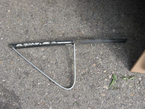 1981 Ford Bronco - A detached car door window frame lies on a paved surface.