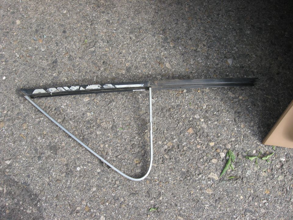 Car door window frame with metal trim and rubber seal on asphalt