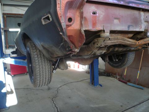 1975 Ford Ranchero - The rear of a vehicle is shown on a lift, revealing its undercarriage components.