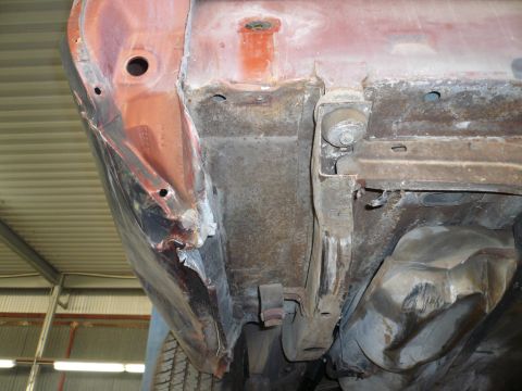 1975 Ford Ranchero - The undercarriage of a vehicle displays significant rust and damage to its frame and body panels.