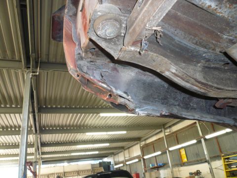 1975 Ford Ranchero - Close-up view of the heavily rusted undercarriage and frame of a vehicle, showing significant wear and extensive corrosion.