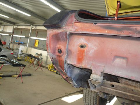 1975 Ford Ranchero - Car body panel repair in progress inside a workshop with tools and other vehicles visible.