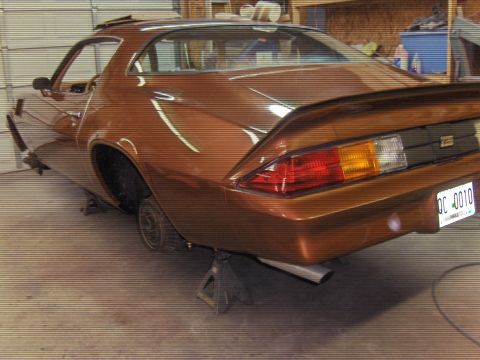1982 Chevrolet Camaro - The rear of a brown 1982 Chevrolet Camaro is shown on jack stands inside a garage.