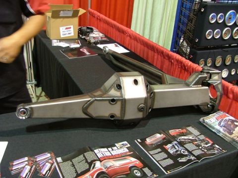 1997 Ford Ranger - A custom-built rear axle assembly is displayed on a table at an automotive show, alongside various car magazines.