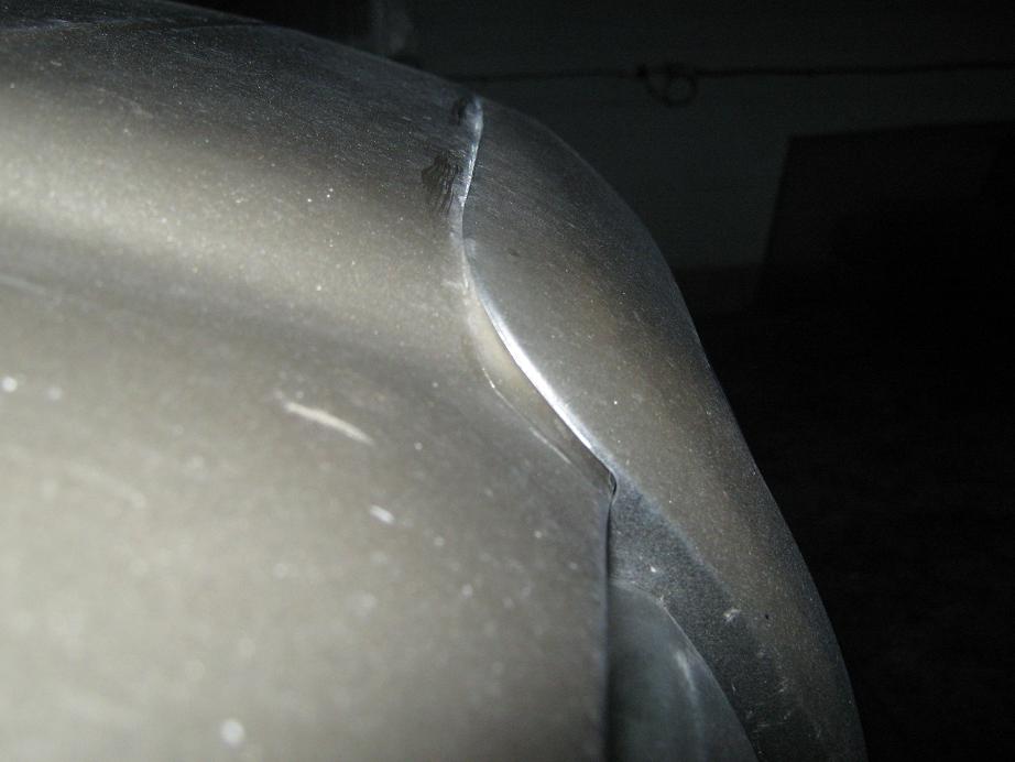 Close-up of a car's metallic gray fender and bumper corner, showing a seam between the two parts