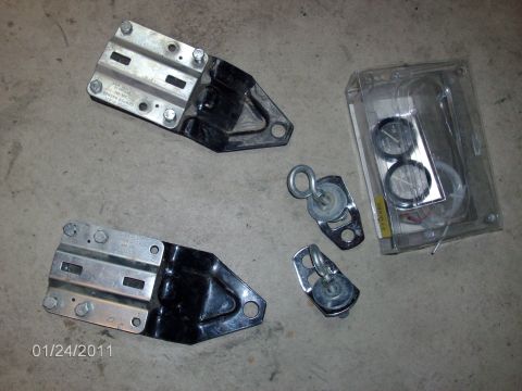 1979 Ford F-150 - A collection of vehicle parts, including mounting brackets and tow hooks, laid out on a concrete surface.