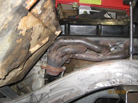 1961 International Scout 800 - Close-up view of a rusty exhaust manifold and engine components, with evidence of frame modifications.