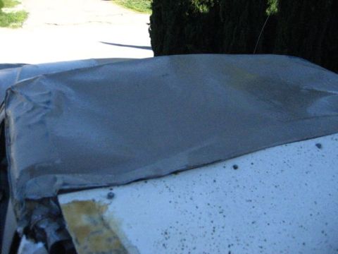1989 Ford Bronco - A vehicle's top is covered with a tarp, revealing some of its underlying structure.