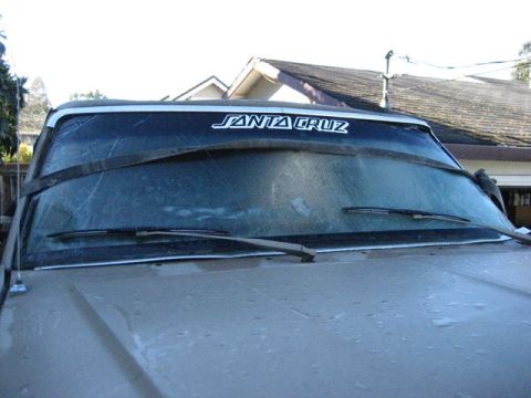 1989 Ford Bronco - Vehicle windshield with a Santa Cruz sticker and a strap holding it.