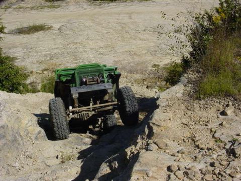 1992 Ford Bronco - This off-road vehicle is navigating a rocky terrain, with its rear visible as it ascends.