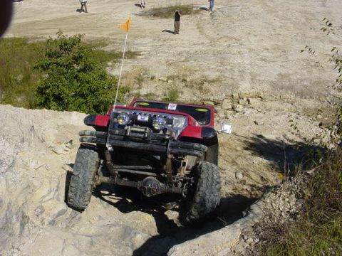 1992 Ford Bronco - A red off-road vehicle navigates a challenging rocky terrain.
