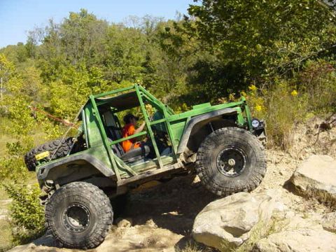 1992 Ford Bronco - Off-road vehicle navigates a challenging rocky terrain on a sunny day.