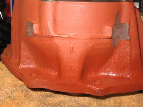 1968 Shelby GT500 - A close-up view of an orange painted metal component, possibly a transmission housing, with a small, raised symbol visible.
