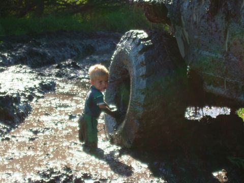 1988 Ford F-150 - A young child stands in the mud next to a large tire, possibly after off-roading.