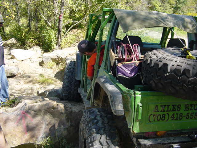 Green off-road vehicle with large tires, spare tire mounted on rear, and text on the tailgate
