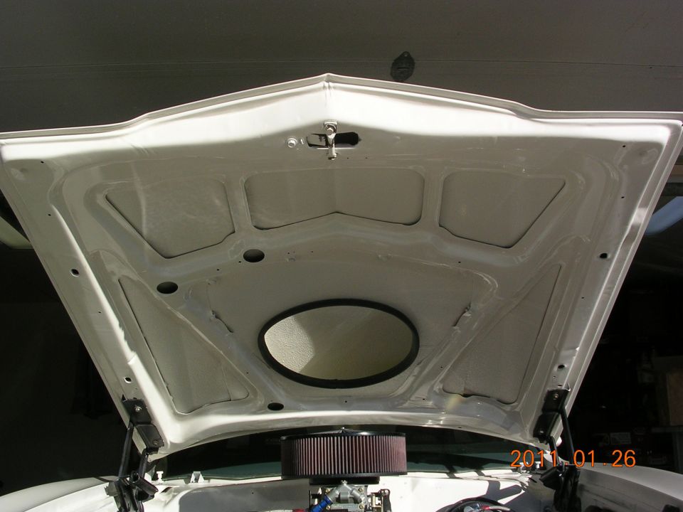 Car hood open showing the engine bay with an air filter and some engine parts. Date stamp visible