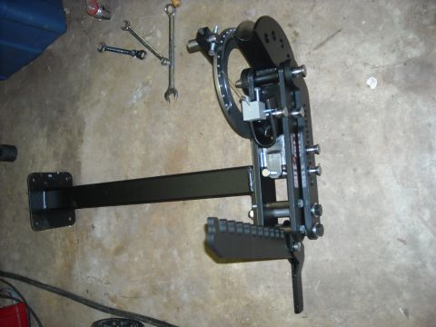 1979 Ford F-150 - A black metal tool, possibly for automotive work, is shown mounted on a concrete floor alongside several wrenches.