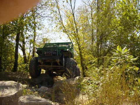 1992 Ford Bronco - Off-road vehicle tackling a challenging rocky path amidst dense foliage.