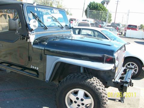 1992 Jeep Wrangler - A black Jeep Wrangler is shown from the front three-quarter view, with other vehicles in the background.