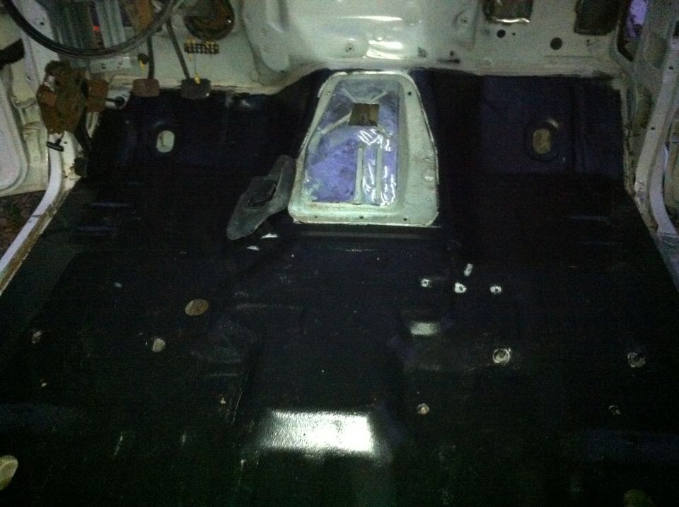 Interior floor of vehicle with black carpeting and exposed metal