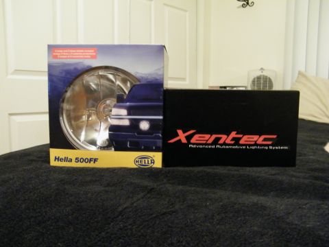 1982 Ford Bronco - Boxes for Hella 500FF and Xentec automotive lighting systems are displayed on a dark surface.