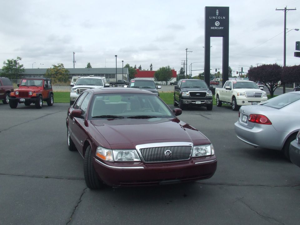 Maroon 2005 Mercury Grand Marquis parked at a dealership lot with other vehicles and a Lincoln-Mercury sign