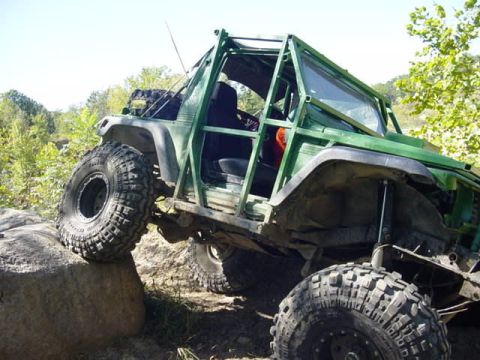 1992 Ford Bronco - This heavily modified off-road vehicle navigates a rocky terrain with its large tires.