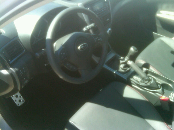 Interior view of a 2011 Subaru Impreza WRX, showing the steering wheel, dashboard, and center console with manual shifter