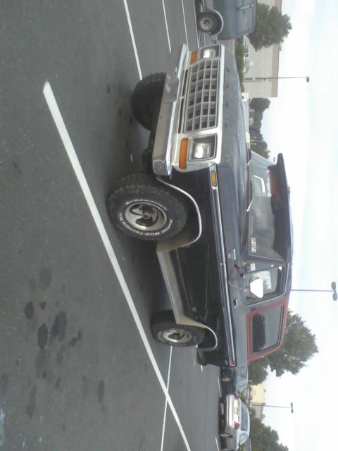 1988 Ford Bronco - This black Ford Bronco with red trim is parked in a lot, viewed from the front three-quarter angle.