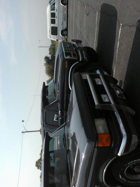 1988 Ford Bronco - Two trucks and a van are parked in a lot under a clear sky.