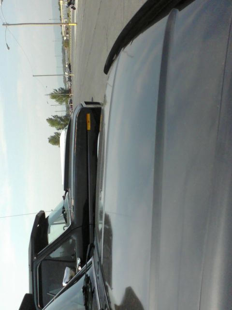 1988 Ford Bronco - A black Ford Bronco with a white top is parked in a lot.