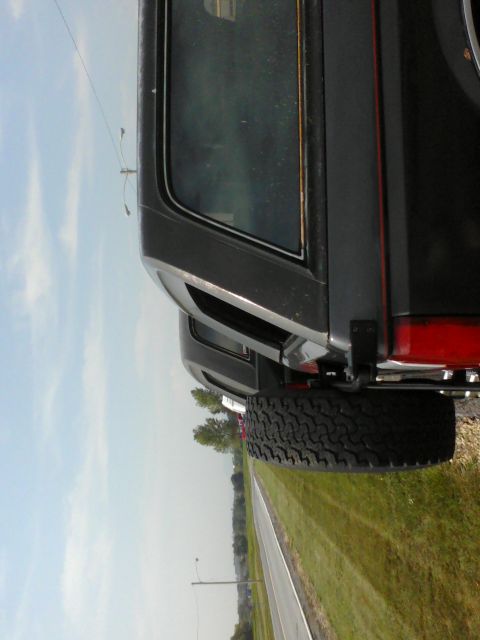 1988 Ford Bronco - A 1988 Ford Bronco's rear quarter panel and spare tire are visible, with another vehicle partially seen in the background.