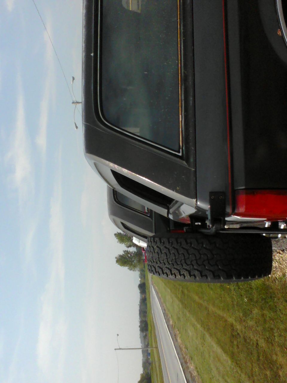 Rear quarter panel and spare tire of a 1988 Ford Bronco parked on a roadside