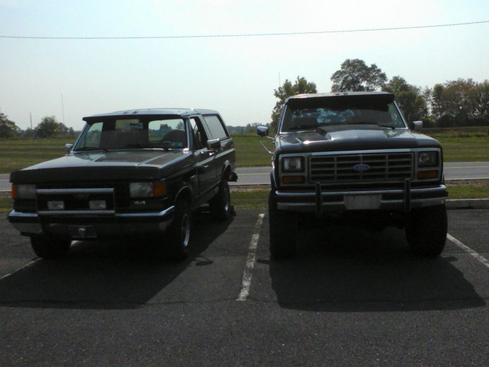 1987 Ford Bronco and a Ford F-Series truck parked in parking spots