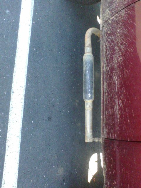 1988 Ford Bronco - A close-up shot of a vehicle's exhaust pipe and a portion of its side body panel.