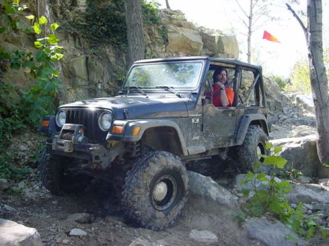 1992 Ford Bronco - A black Jeep Wrangler navigates a challenging rocky terrain on an off-road trail.