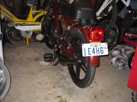 1981 Garelli Rally Sport - A red moped, identified by Garelli branding on the seat, is parked indoors next to other vehicles.