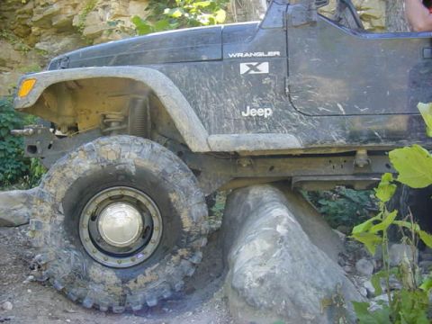 1992 Ford Bronco - Jeep Wrangler's large tires are tested on a challenging rock obstacle.