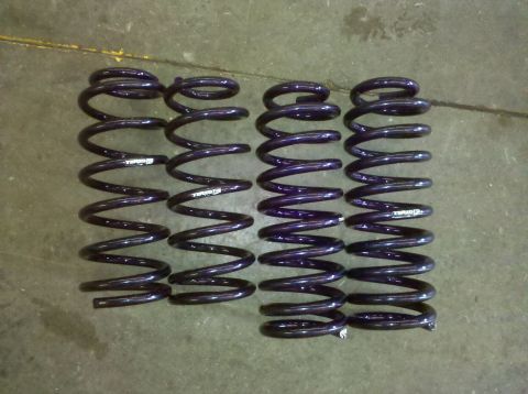 1987 Ford Bronco - A set of four dark purple coil springs are displayed on a concrete surface, with some text visible on the springs.