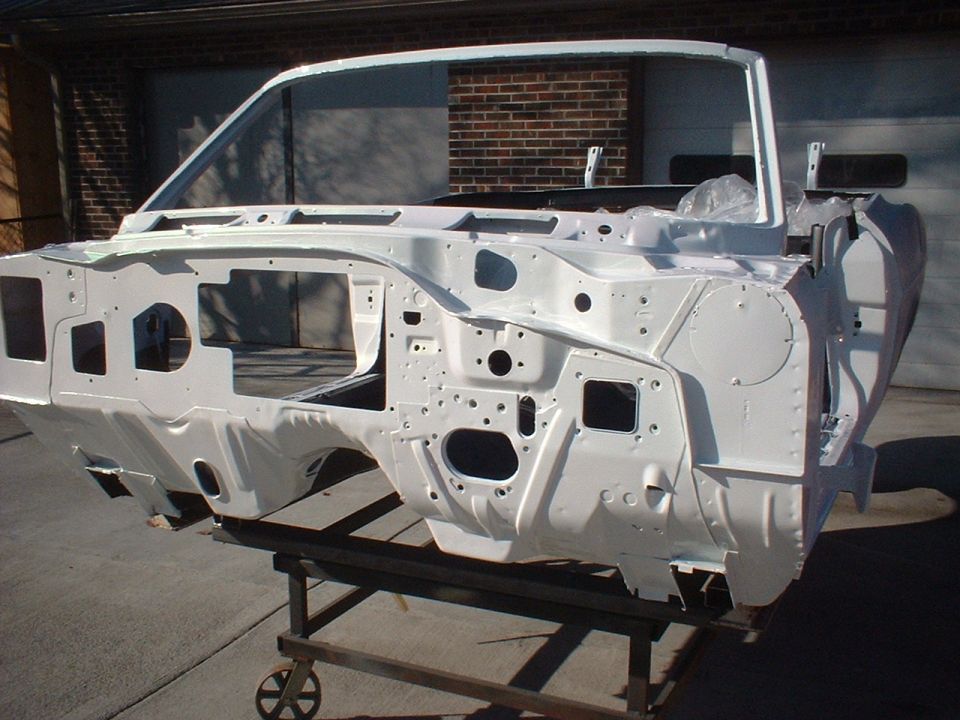 Car unibody frame painted white, mounted on a stand