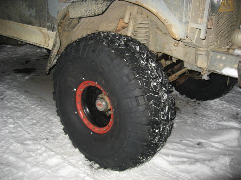 1990 Ford F-250 - A close-up view of a truck's wheel and suspension system in a snowy environment.