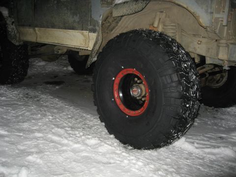 1990 Ford F-250 - A close-up view of a large off-road tire with a red rim, mounted on a vehicle in a snowy environment.