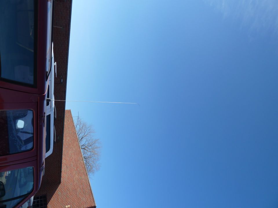 Side view of a red van parked next to a brick building under a clear blue sky