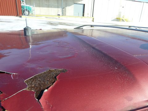 1993 Ford C-150 (Centurion Conversions) - The hood of a red vehicle shows significant rust damage and peeling paint.